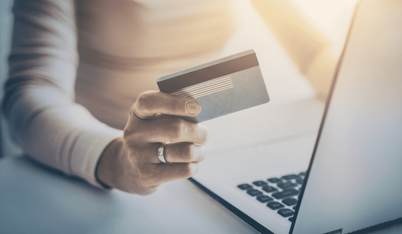 płatność online osoba trzymająca w ręce karte bankową dokonuje platości na laptopie